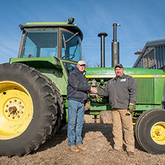 Gary LaGrange, president of Servicemember Agricultural Vocation Education, or SAVE, Farm, shakes hands with T.J. Orender, of Prairieland Partners, who transported this donated tractor to SAVE.