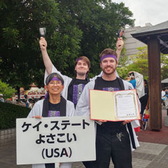 Barbara Johnson, Calum Fletcher and Ryan Kenny pose with signs and noisemakers. 