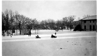 People snow sledding on the east side of Kansas State Agricultural College Auditorium