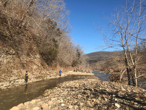 Langston and graduate student Clay Roberson measuring the height of the valley wall, January 2021. This photo shows the Buffalo River, the blocky talus pile of collapsed valley wall material across the river, and the bedrock valley wall.
