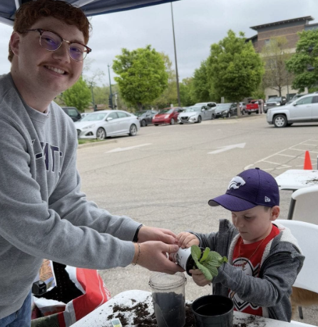 Student helping child plant