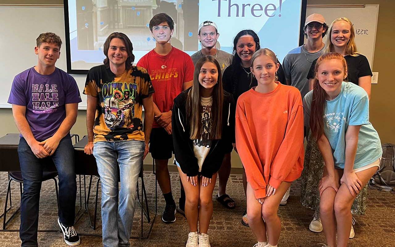 A class leader poses for a photo with their group of LEAD 212 students in a classroom.