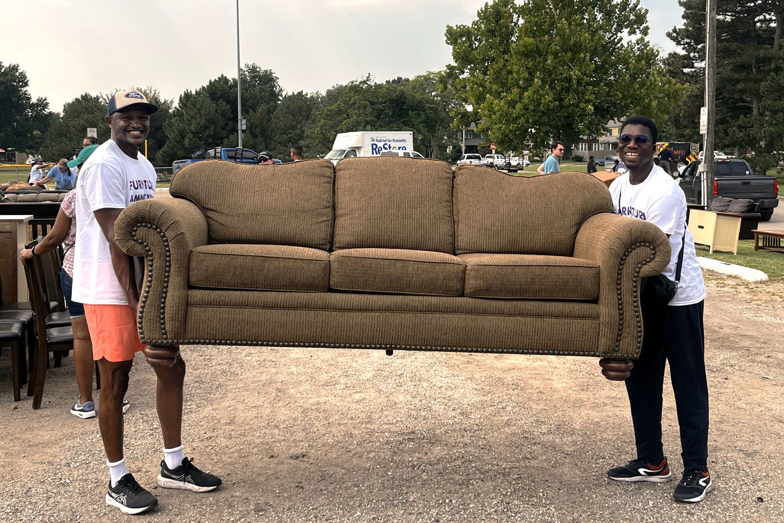 Two volunteers are carrying a couch to be loaded