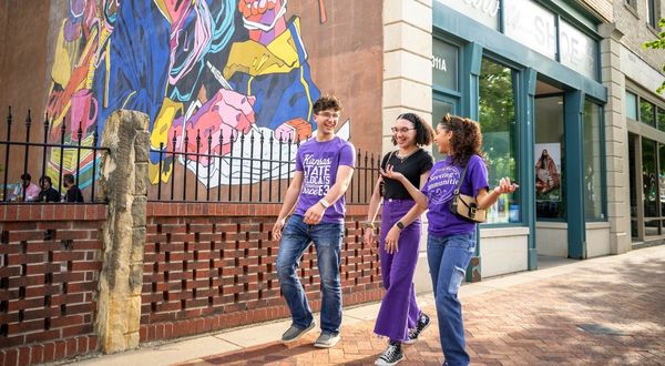 Three people walking on sidewalk
