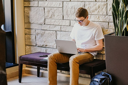 Student using a laptop in the leadership studies lobby
