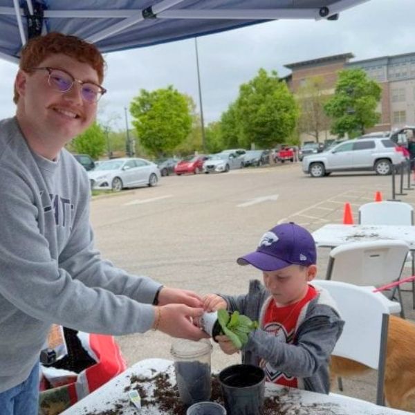 Student helping child plant