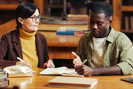 professor working with a student in the library