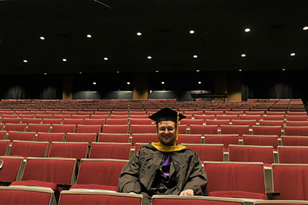 student in gap and gown in an auditorium