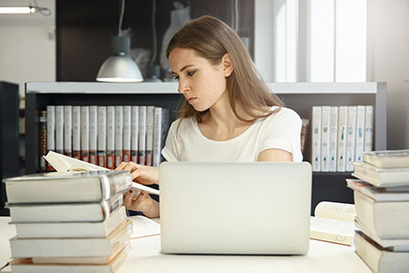 female student looking at a textbook in the library