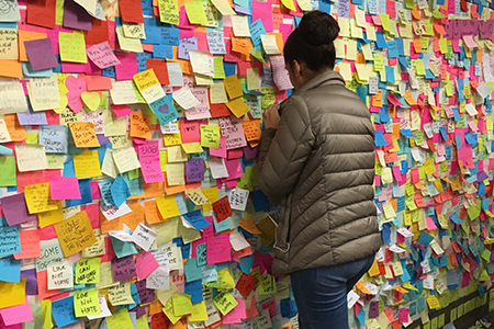student adding to a post-it note wall