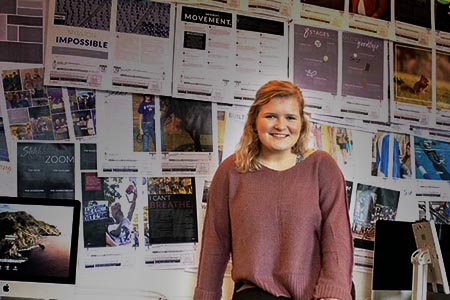 student with news spreads behind her on the wall