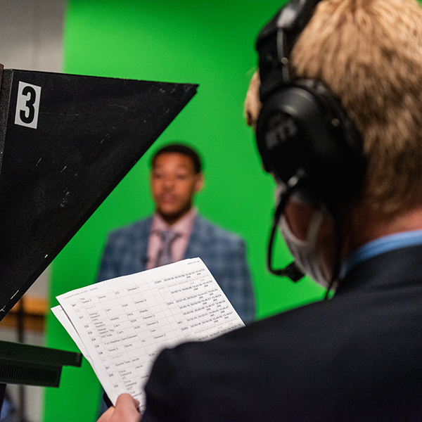 student in the news studio reading a script