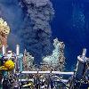 Black smoke erupts from a seafloor vent called a hydrothermal system. The black smoke consists of an abundance of dark, fine-grained, suspended metal particles that form when hot fluid mixes with cold seawater.  |  Photo credit: Woods Hole Oceanographic Institution Archives