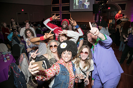 Retro-costumed attendees of the 2017 Pink and Purple Polyester Party. 