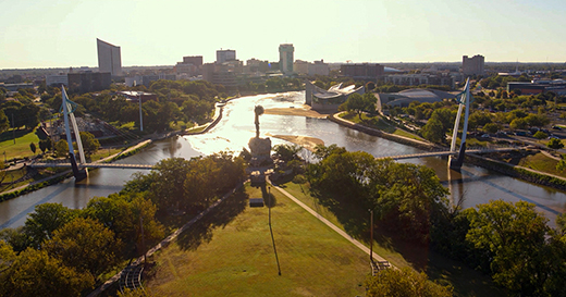 This image shows the Keeper of the Plains at the Arkansas River with the downtown Wichita skyline in the background. 