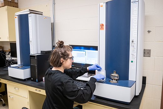 Alyssa Friesen, diagnostic technician in the KSVDL's bacteriology laboratory, loads a target into the MALDI-TOF mass spectrometer for rapid identification of microorganisms, primarily bacteria, from clinical samples submitted to the laboratory.