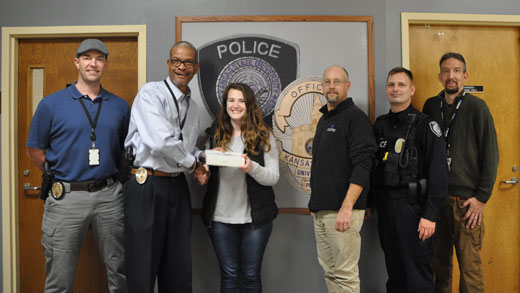 Andrew Moeller, Ronnie Grice, Madeline Triggs, Jason Blackburn, Michael Boller and Dustin Newton smile as Triggs is presented with an iPad from LiveSafe