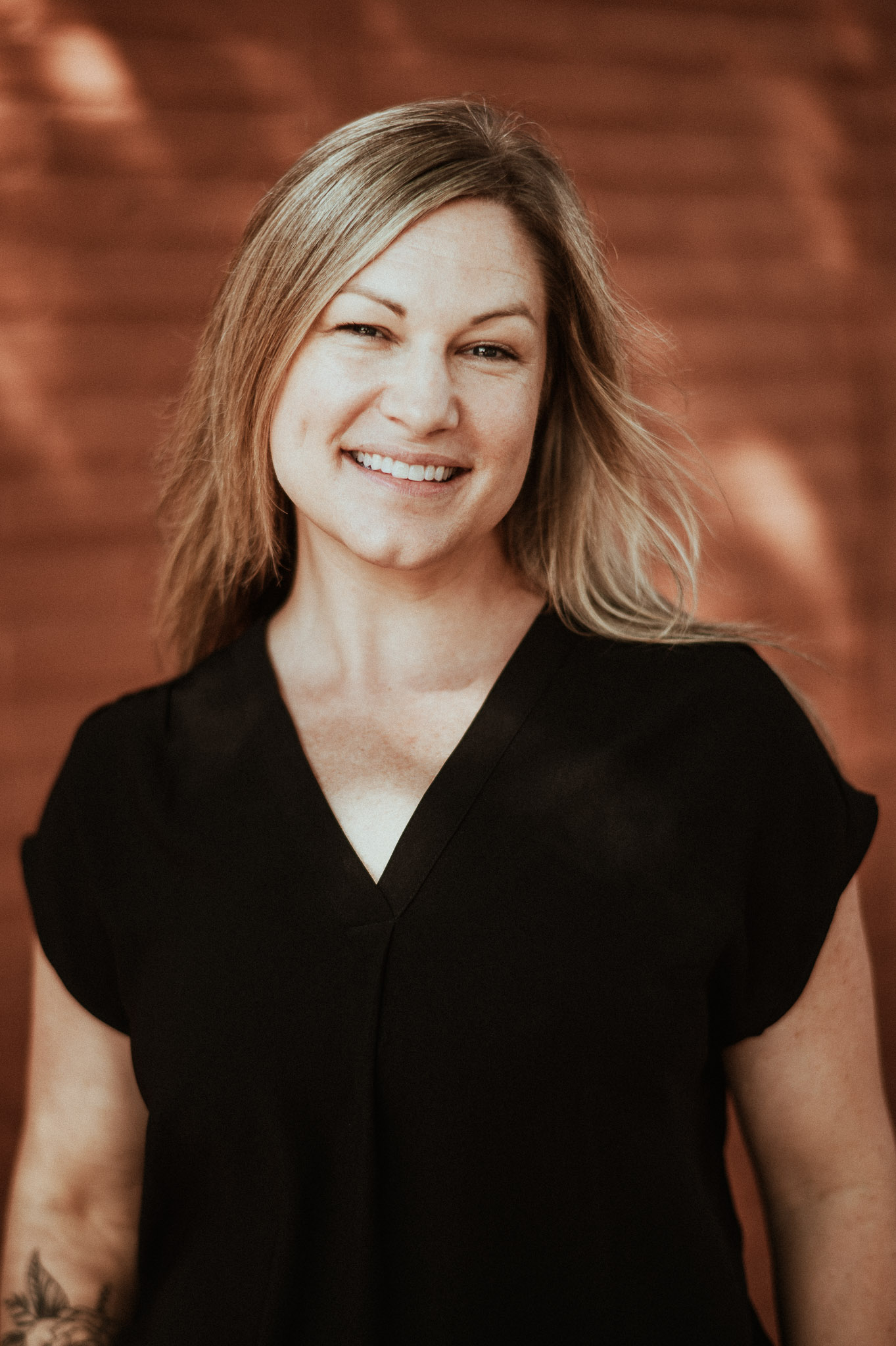 Maris Deaver headshot with a black shirt and a brown gradient background