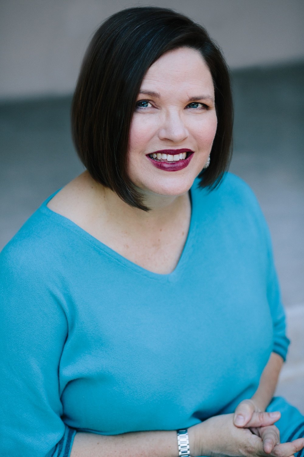 a women with dark hair and a blue top smiling