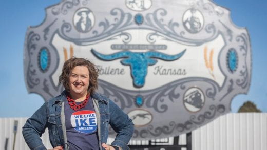 Julie Weeks stands in front of large belt buckle attraction