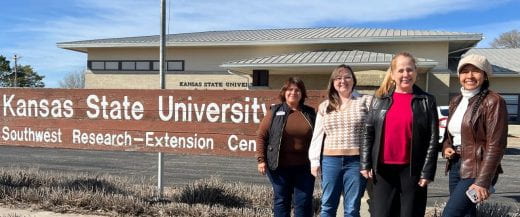 Raelynne Hale and Maria Theresa DePaoli with two others in front of K-State's Southwest Extension building sign