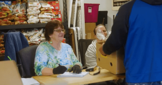 Screenshot from video showing volunteers distributing box of food to someone