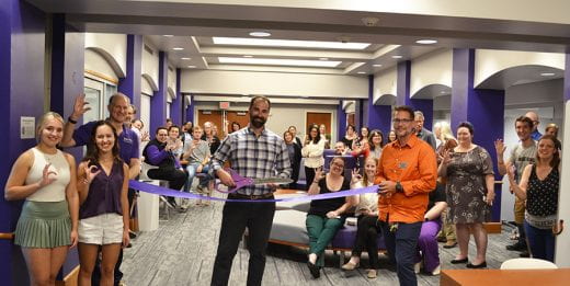 Photo of ribbon-cutting event showing Nate Birkhead with scissors