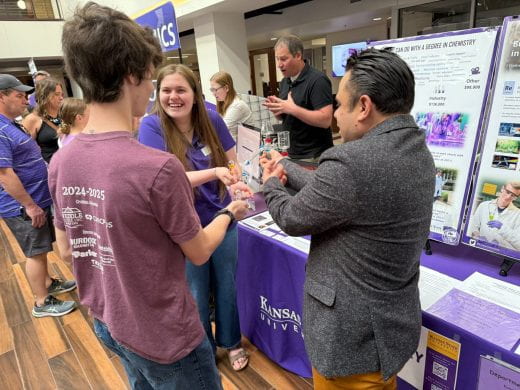 photo of visitor and volunteers at chemistry table at Open House