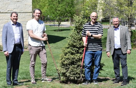 Roots of Research Awardee Zak Ratajczak and others holding ceremonial shovels near tree