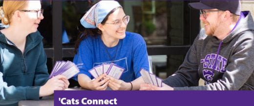 three smiling people sitting at a table outside