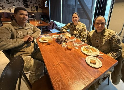 Table of smiling party guests in army uniforms