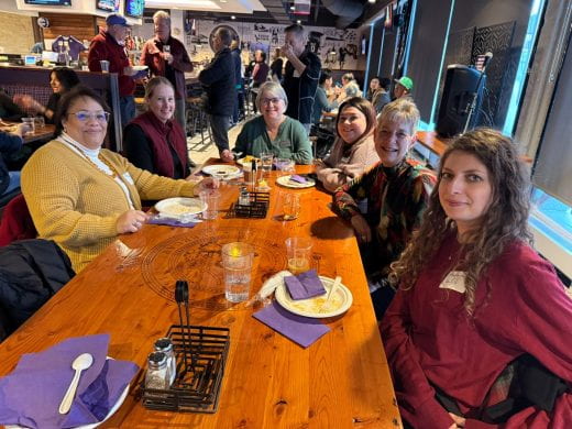 Table of people smiling with many in background