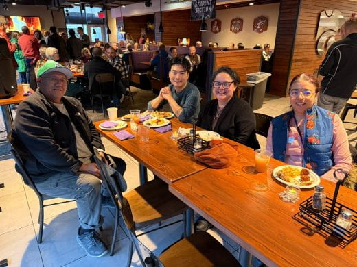 Table of people smiling with many in background