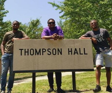 geography grad students standing by Thompson Hall sign