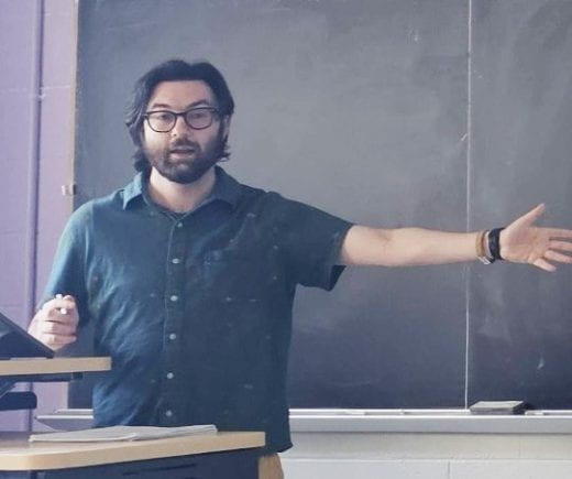 Photo of Josh Venick teaching at front of classroom