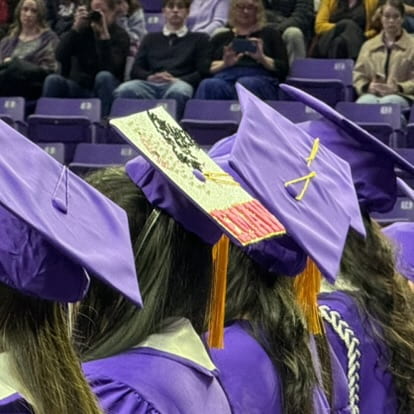 closeup of back of a few students' heads and one adorned cap