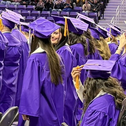 graduating student smiles at neighboring student