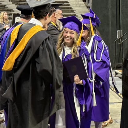 graduating student with big smile as she shakes professors' hands