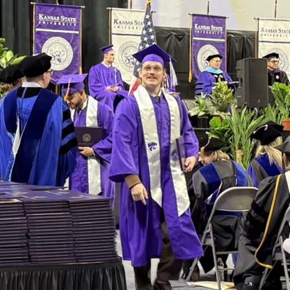 student smiles at people in audience as makes way back to seat