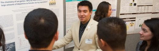 photo of students talking to people in front of their research posters