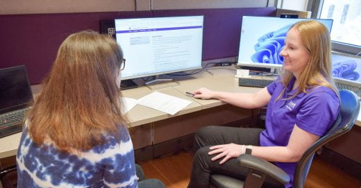 Photo of advisor and student in office with computer monitors