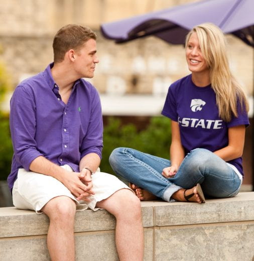 Photo of two people chatting while sitting on a limestone wall
