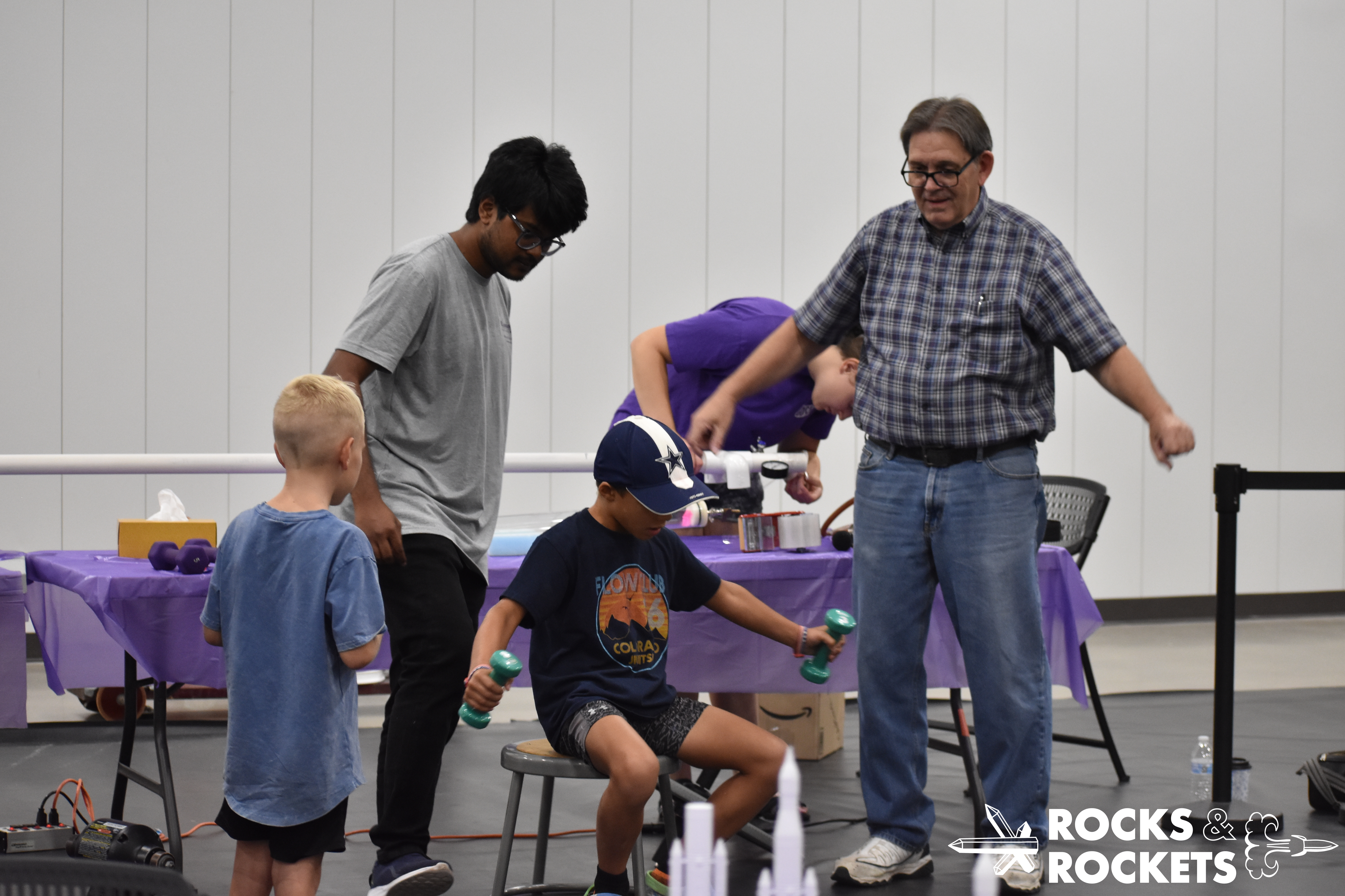 young participant lifts weights at physics demo