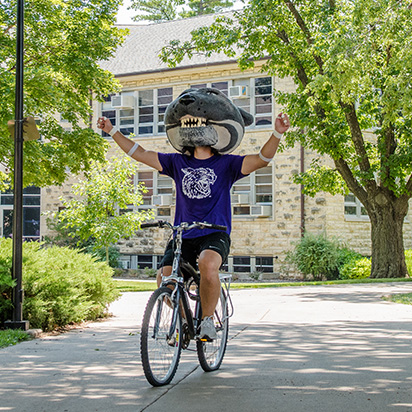 Mascot Willie the Wildcat riding a bike