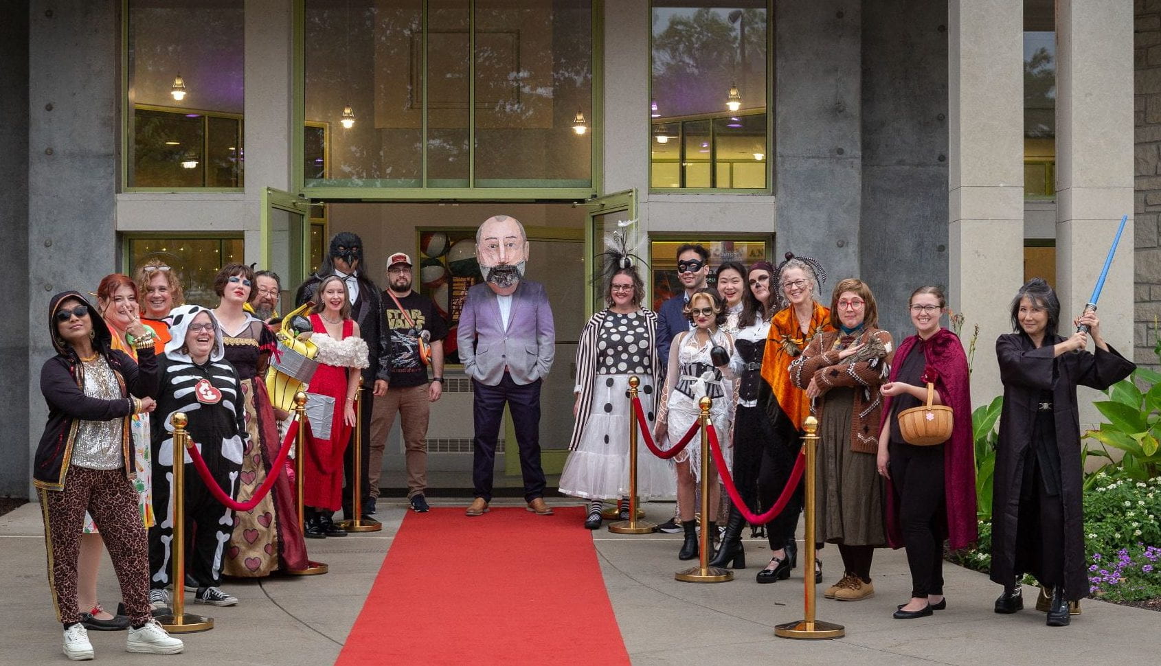 Beach Museum of Art staff members in varied costumes pose at the entrance of the museum.