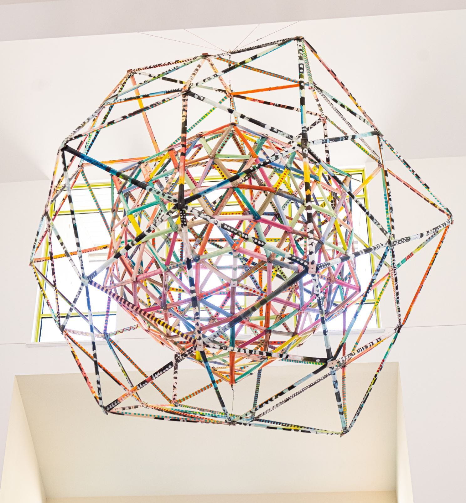 An icosohedron sculpture using metal tubing, bolts and nuts, and cotton thread, hanging from the ceiling at the Beach Museum of Art.