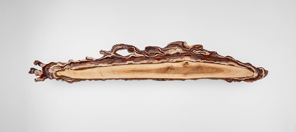 Several tiny beads stuck together in rows on an uneven surface to create a topographical sculptural work.