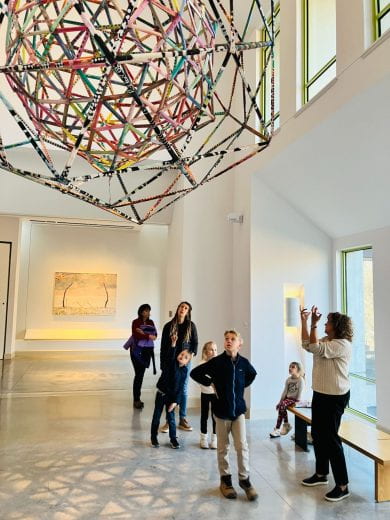 Art class participants explore the sculpture "Kansas Meatball" by Alan Shields hung from the ceiling at the Beach Museum of Art.