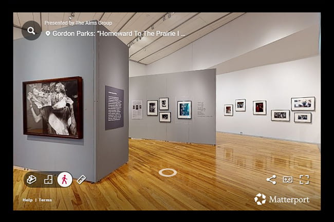 Exhibition gallery with several framed artworks displayed on photos, most showing photographs of people. 