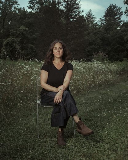 A woman sitting on a chair placed in a natural prairie environment